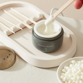 stirring a mini wax heater with waxing pellets from the london beauty company