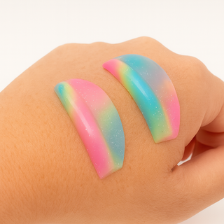 Colorful rainbow-shaped gel eyelash lifting shields on a hand against a white background