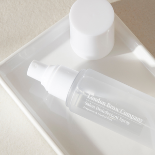 White bottle of London Brow Company Salon Disinfectant Spray on a white tray.