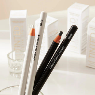 Two eyebrow pencils from the London Brow Company on a white surface with a blurred background.